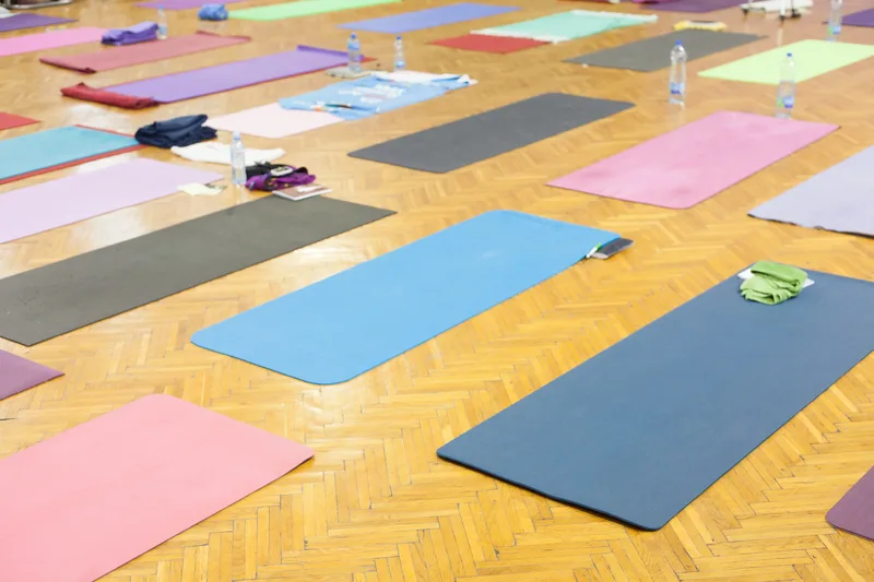 Colourful yoga mats laid out across a warm wooden floor before class