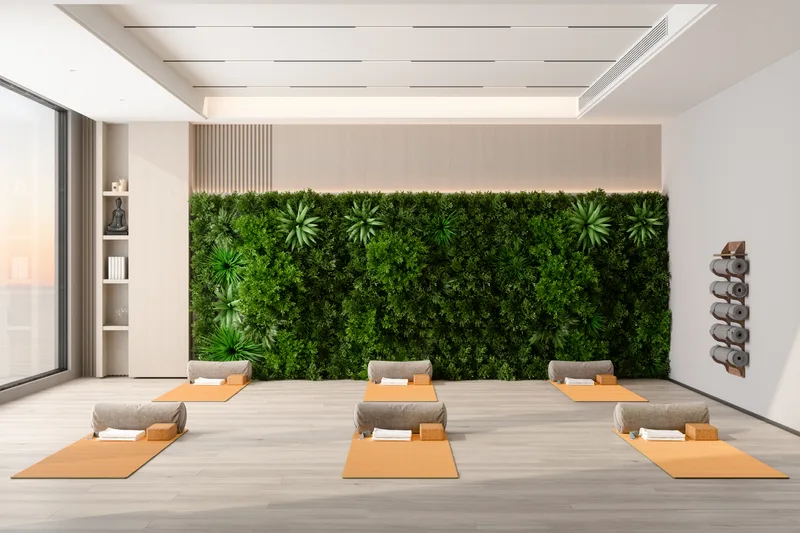 Bright studio room with a living plant wall and mats with bolsters laid out in two calm rows