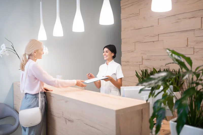 Front desk with a light wood counter where a coordinator welcomes a patient