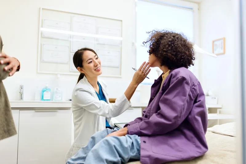 Dermatologist examining a young patient's facial skin during an acne assessment visit