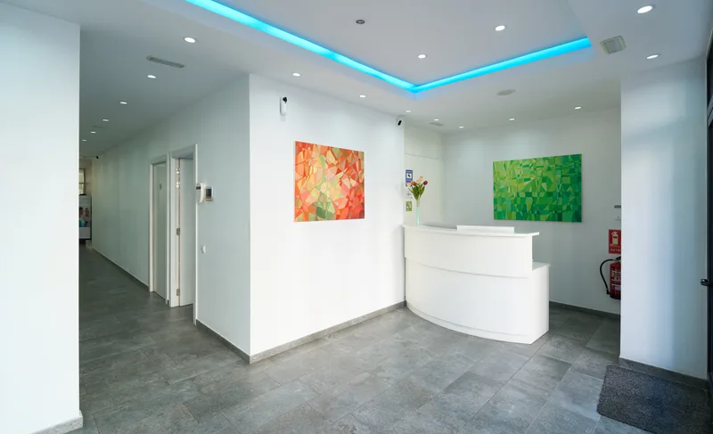 Aster Dermatology's bright reception area with a white curved front desk and colorful artwork