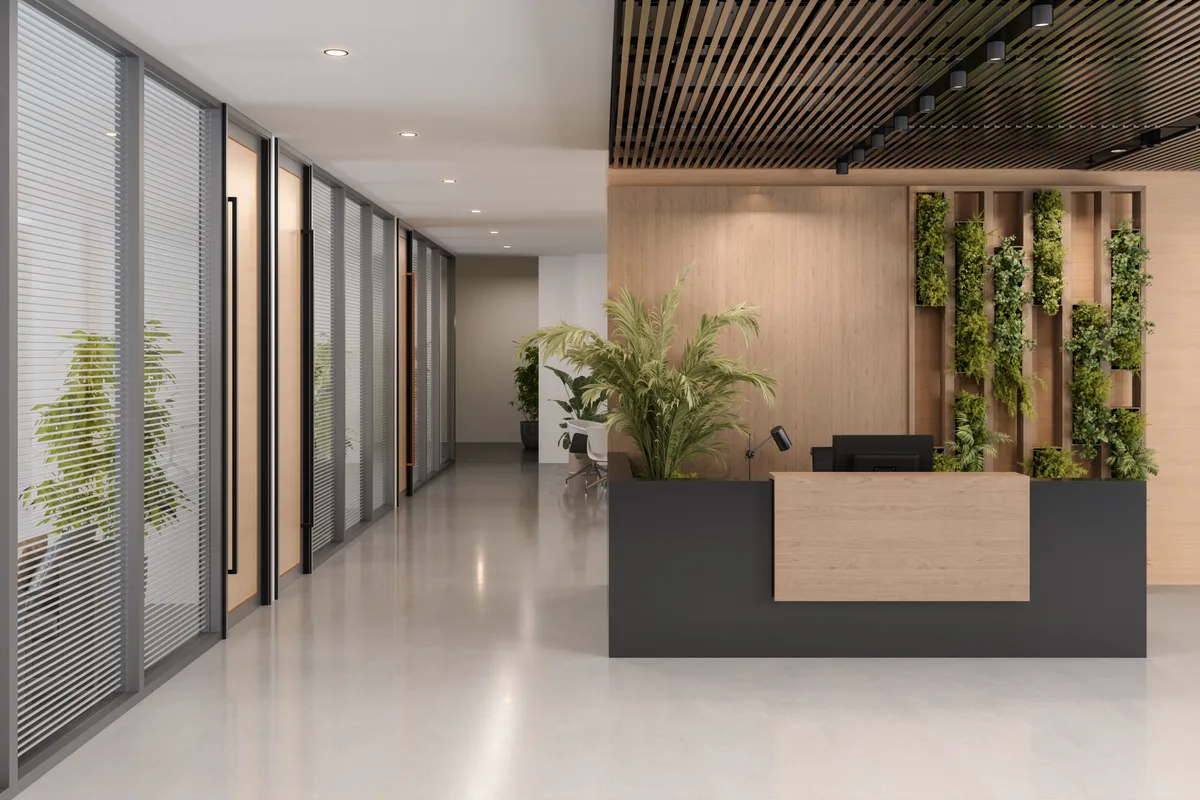 The Atrium clinic lobby — a calm, plant-lined reception with a warm wood welcome desk and glass-walled consult rooms