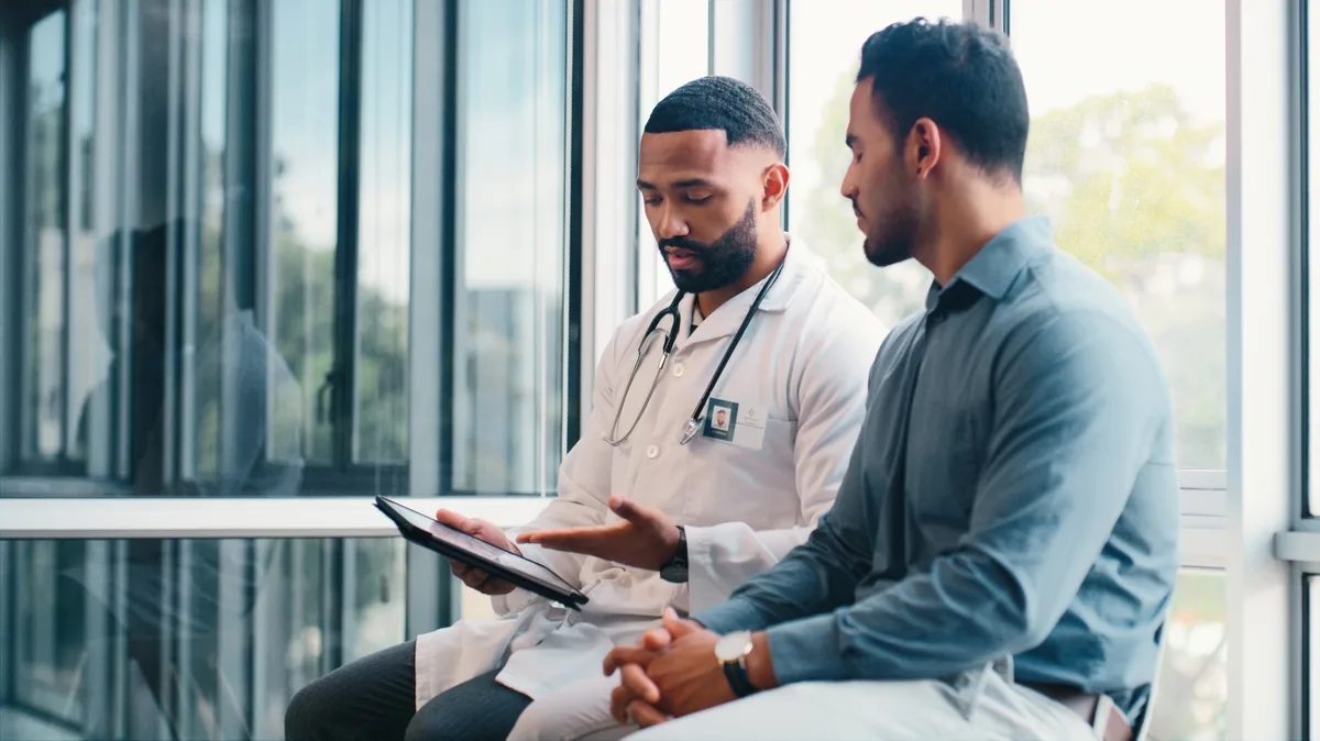 An Atrium physician reviewing results on a tablet beside a member, seated together by a bright window