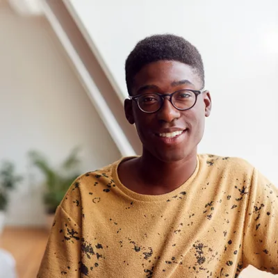 Jordan Abara, a young therapist in glasses and a mustard shirt, smiling in a bright office