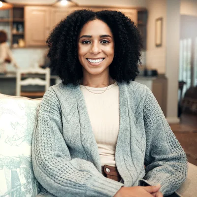 Amara Whitfield, a therapist with curly hair in a grey knit cardigan, seated on a sofa