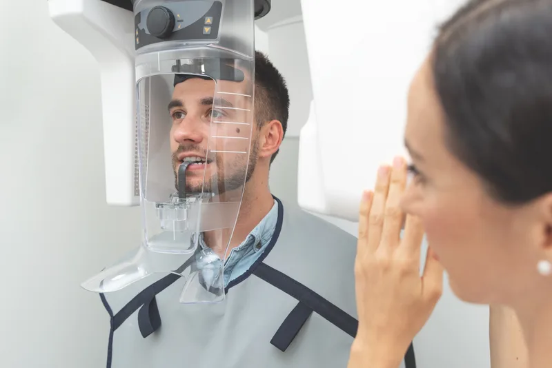 Adult patient standing in a 3D imaging machine while a team member explains the scan