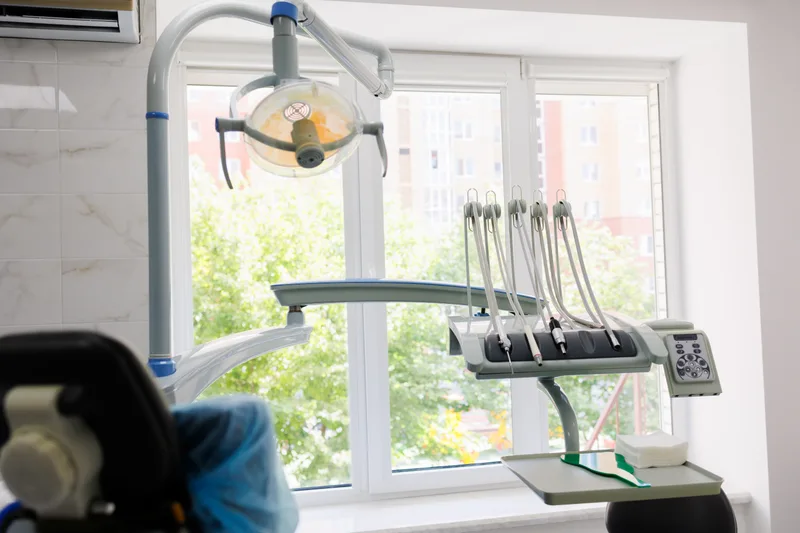 Bright treatment room with a large window, green trees outside and a patient chair