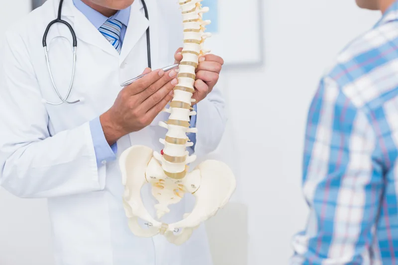 Clinician pointing to a spine model while explaining a patient's back pain