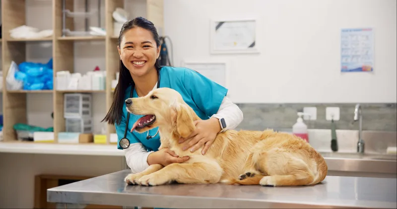 Dr. Maya Okafor smiling beside a golden retriever resting on the exam table