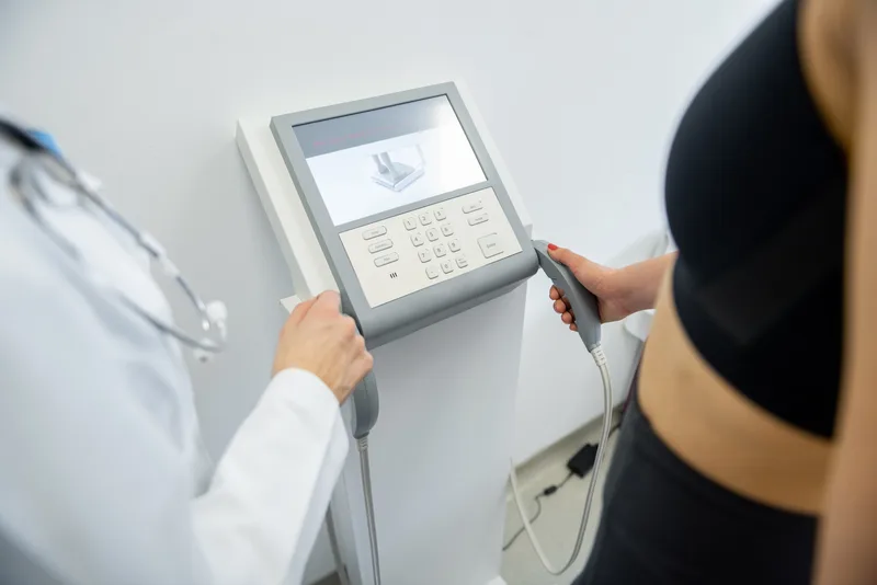 A clinician sets up a body composition scale while a patient holds the hand grips