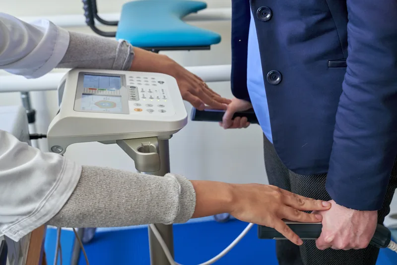 Close view of hands on the grips of a body composition analyzer in a clinic