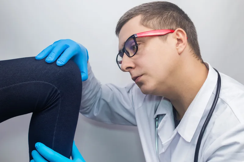 Orthopedic doctor bending a patient's knee to test the joint