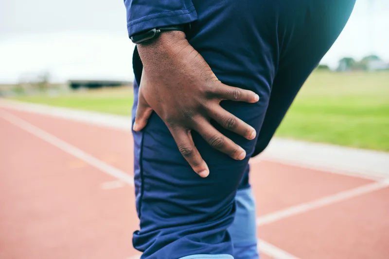 Runner on a track holding the side of his hip