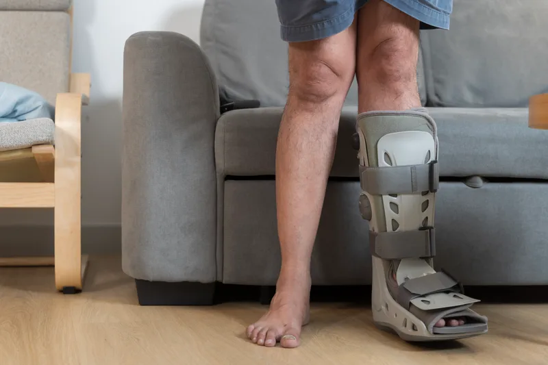 Person standing at home in a medical walking boot on one foot