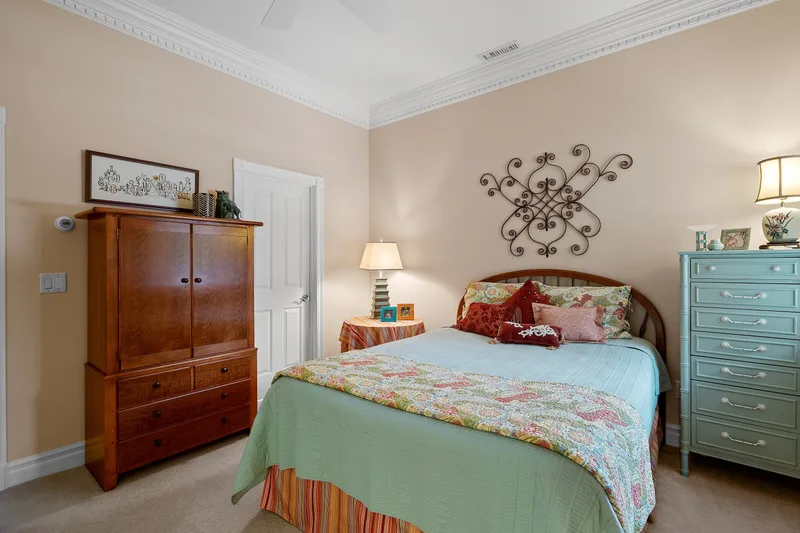 A suite bedroom with a quilted bed, a wooden wardrobe and a dresser from home