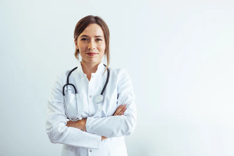Dr. Elena Marsh in a white coat with a stethoscope, arms folded, smiling calmly