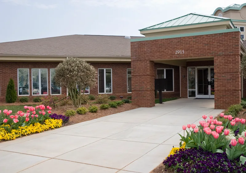 Single-storey brick clinic entrance with spring tulips along the walkway