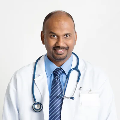 Portrait of Dr. Rajan Pillai, chiropractor, in a white clinic coat with a stethoscope