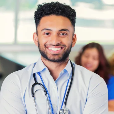 Dev Raman, physician assistant, smiling in a light-filled clinic
