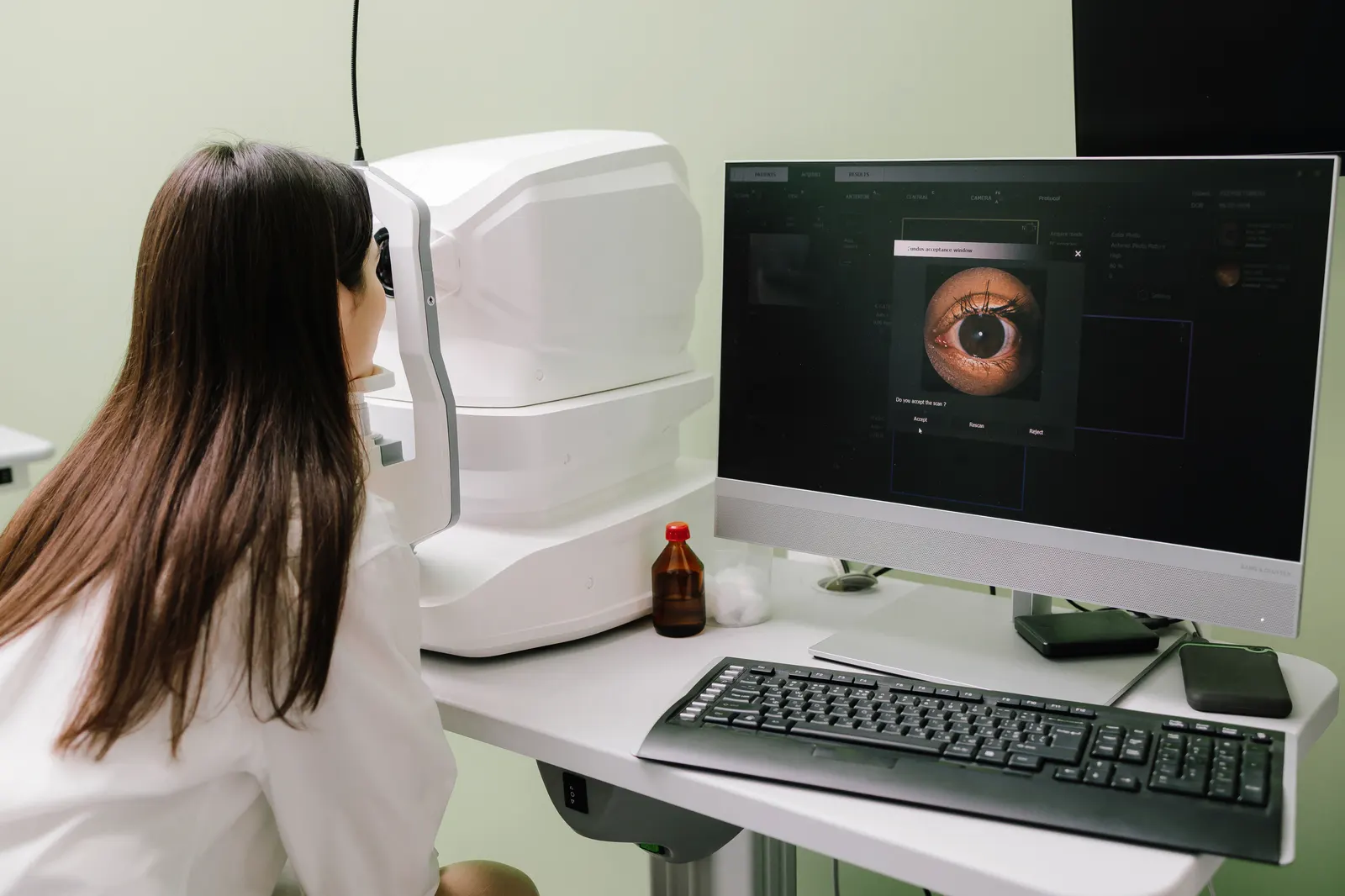 A patient at the OCT scanner while the monitor shows a magnified image of her retina