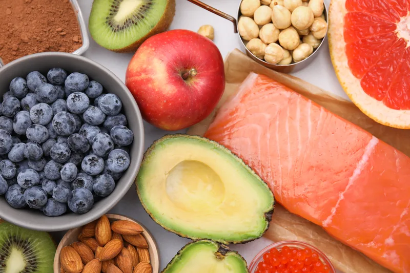 Blueberries, salmon, avocado, apples, nuts and citrus laid out on a table