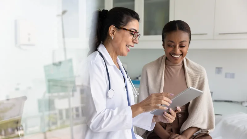 A doctor shows a smiling patient her lab results on a tablet