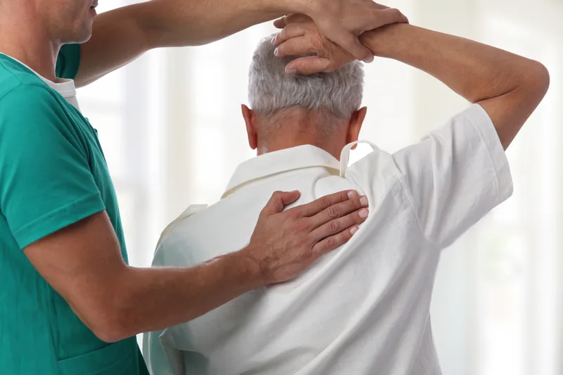 Chiropractor performing a gentle neck and shoulder mobilization on an older patient