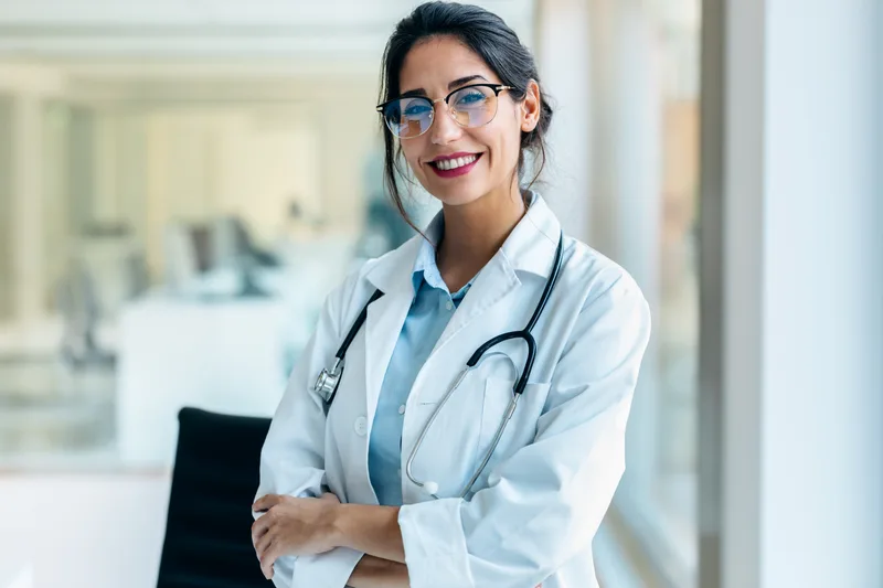 Portrait of Dr. Naomi Castellano in a white coat, smiling in a bright clinic office