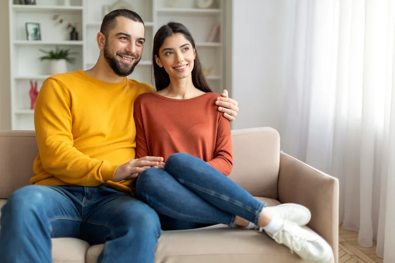 A smiling couple relaxing together on a sofa at home