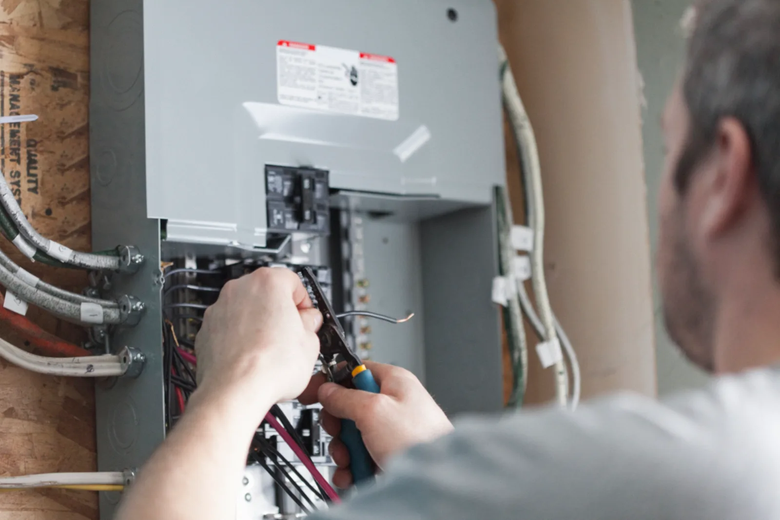 Electrician terminating conductors inside a residential breaker panel during a 200 amp service upgrade