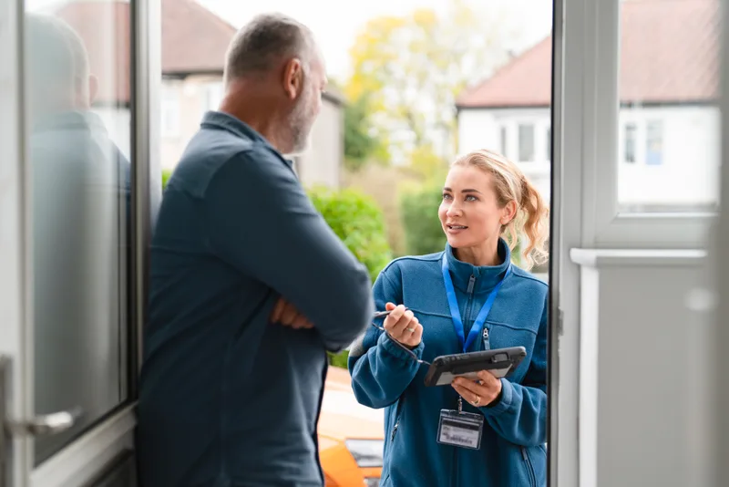 Restoration coordinator with a tablet talking with a homeowner at his front door