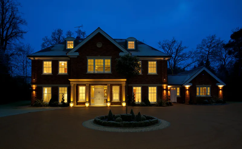 A brick family home at dusk with every window lit