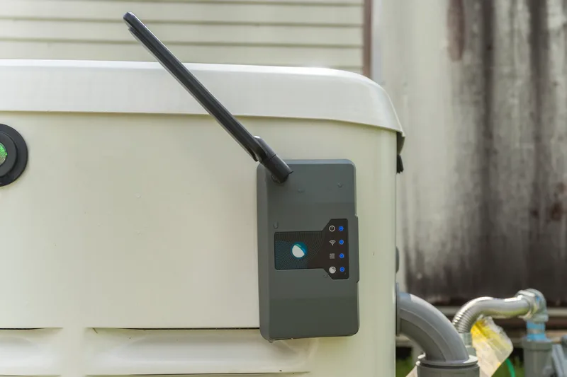 Close-up of a remote monitoring module with status lights mounted on the side of a standby generator enclosure