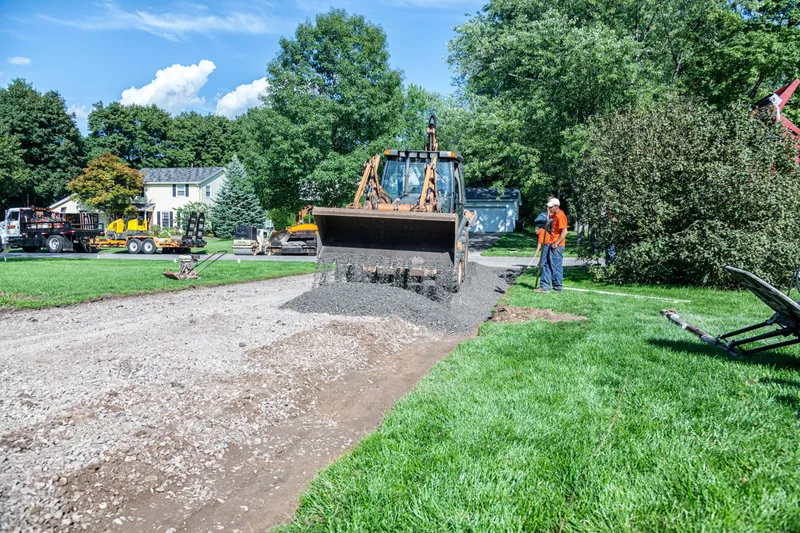Loader spreading crushed gravel for a new driveway base