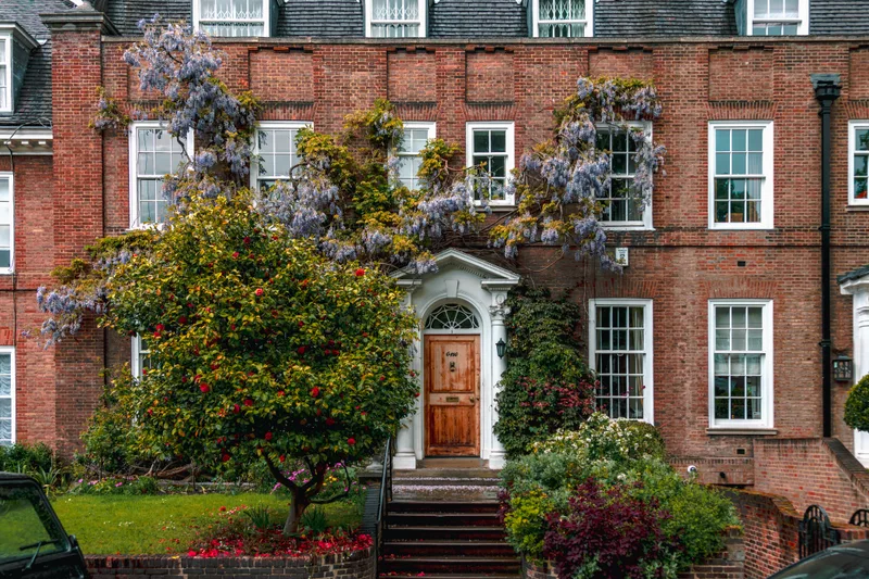 Red brick Georgian house with rows of white multi-pane windows and a wood front door