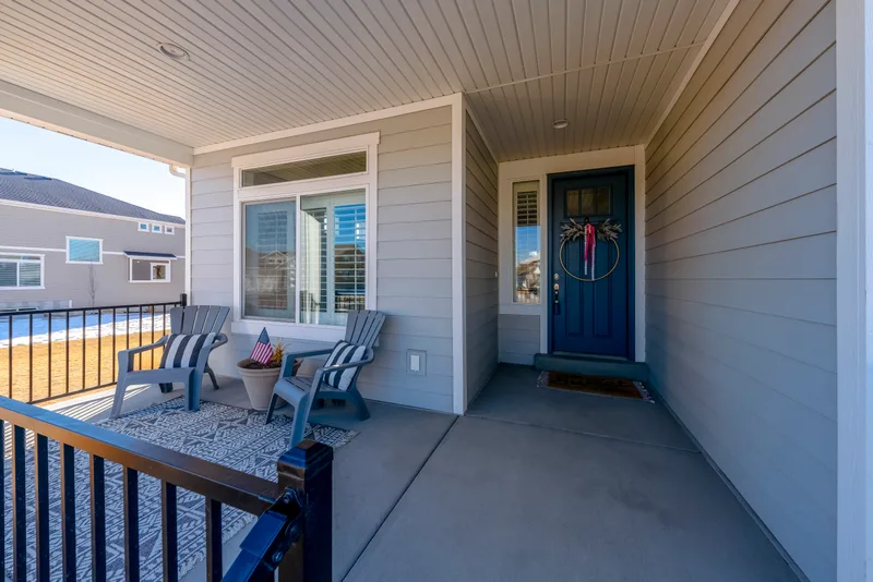 Covered front porch with a navy blue entry door flanked by tall glass sidelites