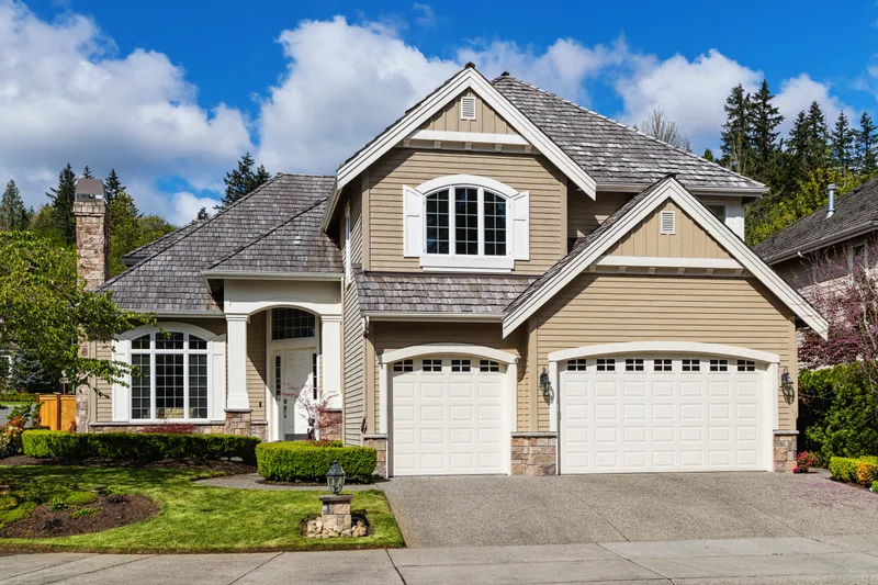 Two-story suburban home with two white garage doors with arched windows