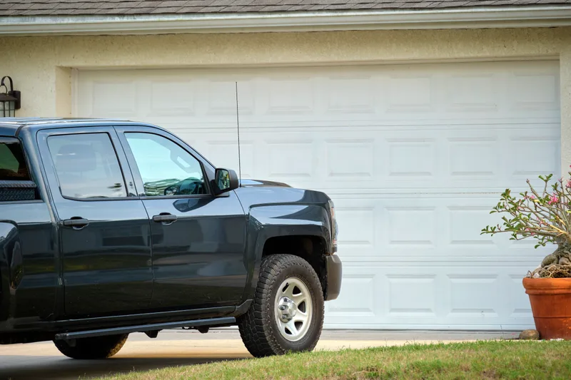 White short raised-panel double garage door behind a parked pickup truck