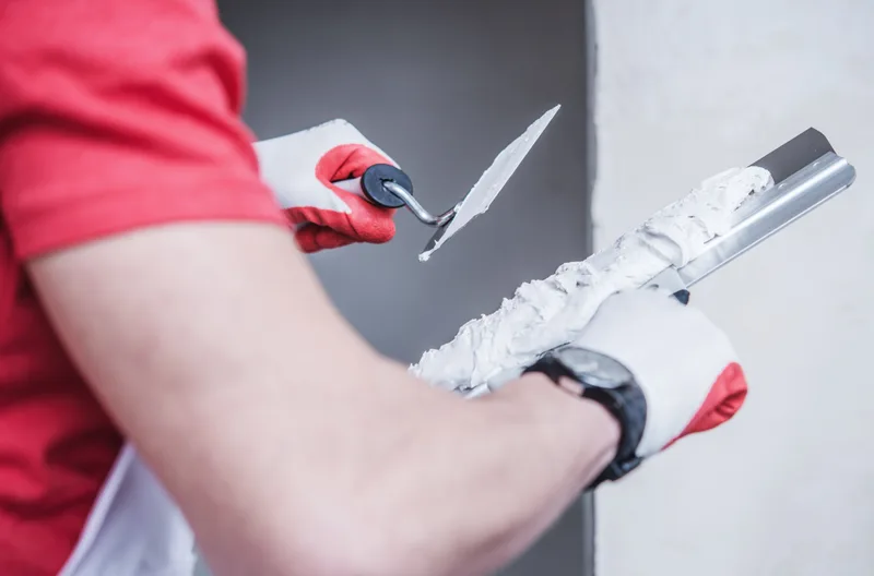 Gloved hand loading drywall compound onto a taping knife