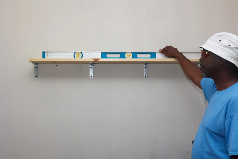 Handyman checking a new wall shelf with a long spirit level