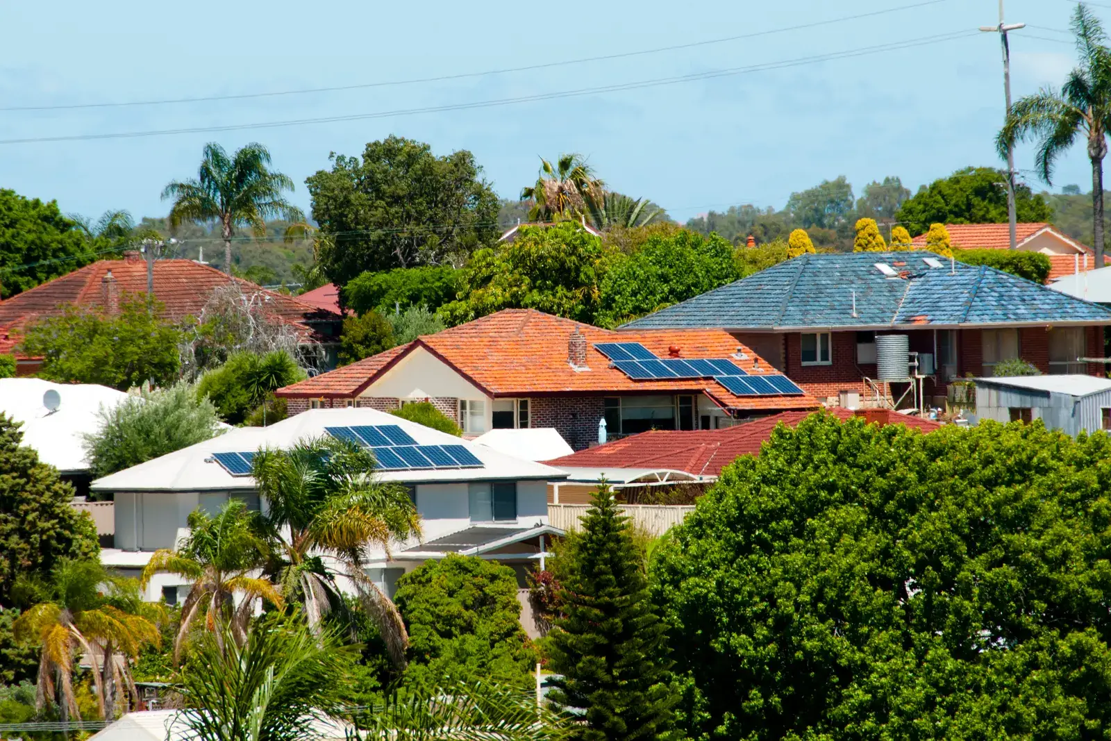 Neighborhood rooftops with solar arrays installed on three adjacent homes