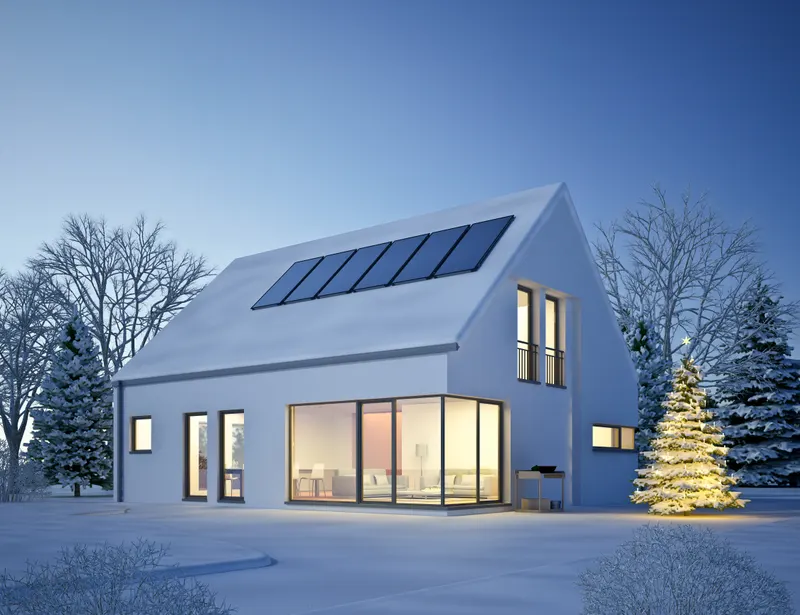 Modern house with a standing-seam metal roof and solar panels surrounded by snow