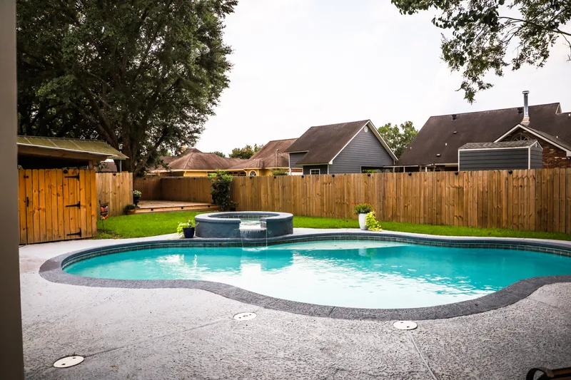 Backyard pool and spa surrounded by a wood privacy fence