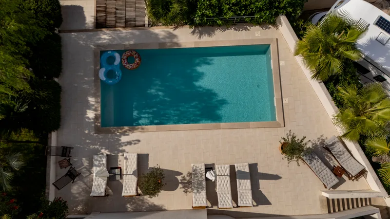 Aerial view of a rectangular courtyard pool surrounded by a stone deck and lounge chairs