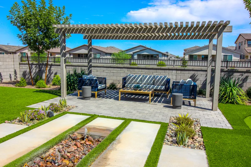 Backyard pergola over an outdoor lounge, with paver walkways and lawn