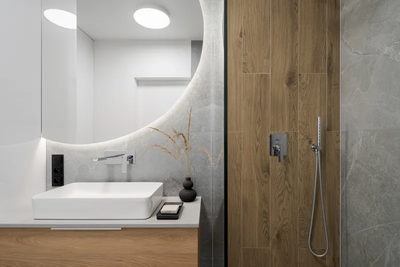 Modern bathroom with a floating vanity, round mirror and wood-look porcelain tile