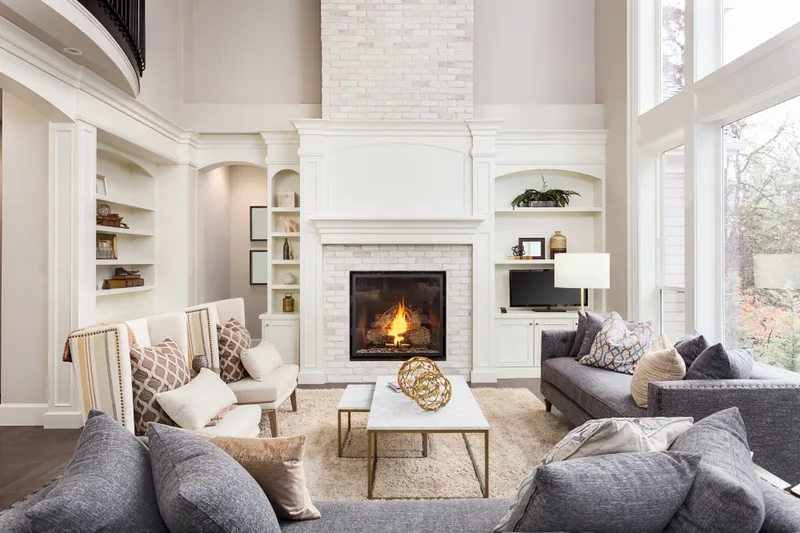 Tall living room with a fireplace, grey sofas and brown hardwood floors
