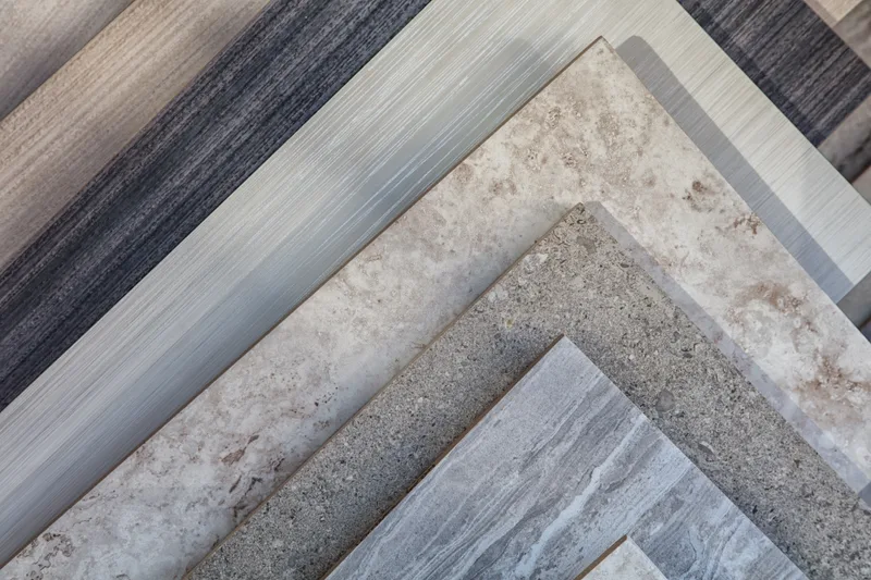 Fanned stack of flooring samples in greys, stone tones and weathered wood looks