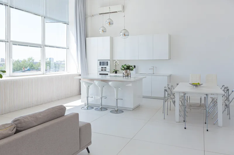 Sun-filled all-white loft kitchen and dining area, freshly cleaned and completely empty of clutter