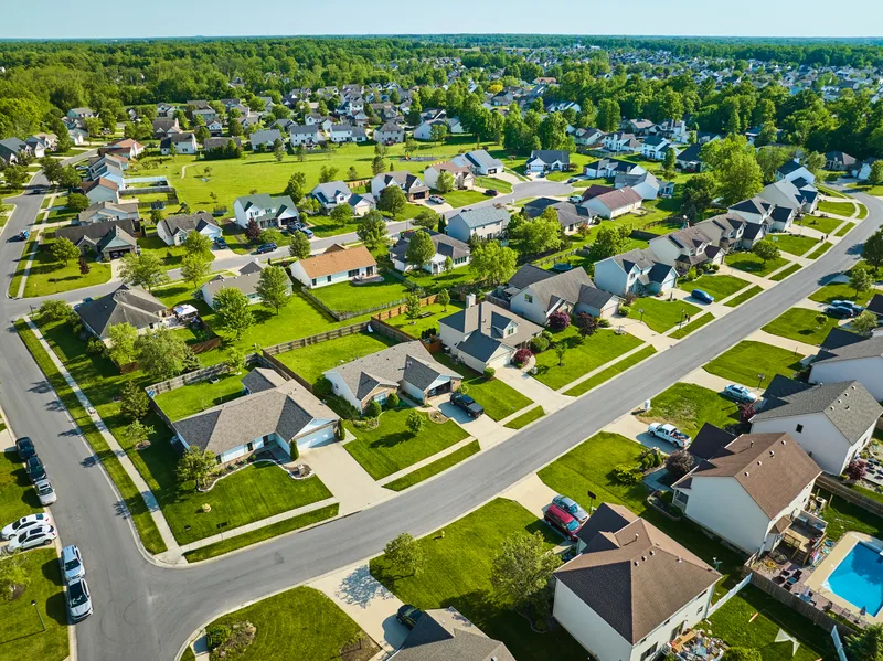 Aerial view of a suburban neighborhood with green summer lawns